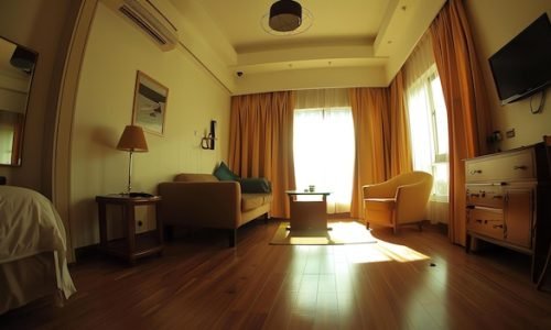 comfy-hotel-room-with-large-bed-sofa-tv-room-is-decorated-warm-colors-has-plenty-natural-light_14117-82134
